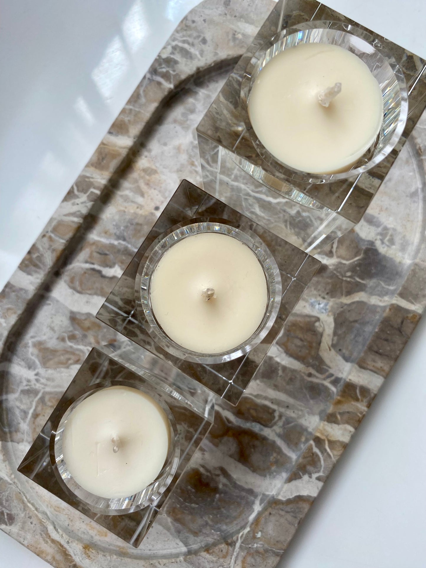 Three white candles in glass holders on a stone surface.
Decorative candle holders set. 
Crystal tea light candle holders, set of 3, house decor ideas, gift ideas.
Elegant, minimalist and modern candle holders.
Timeless house decor. Coffee table styling, dinning setting styling. 
Luna Deco
