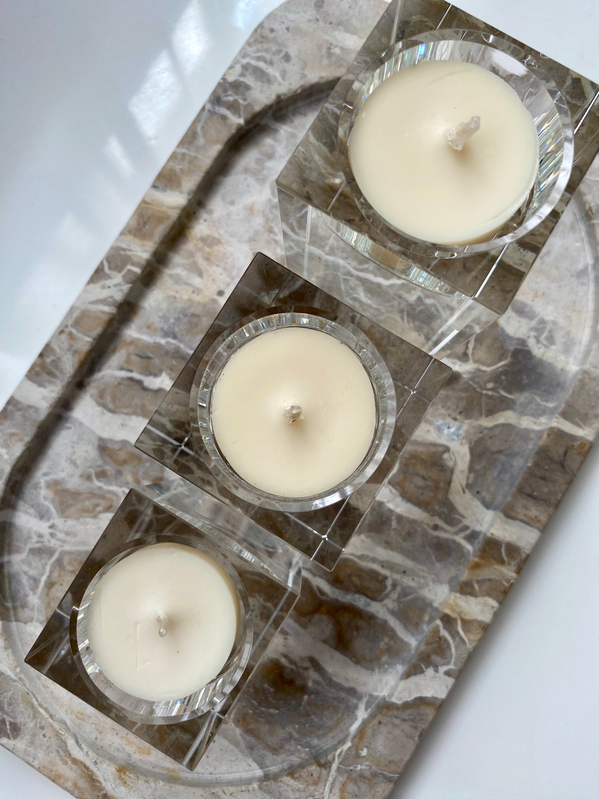 Three white candles in glass holders on a stone surface.
Decorative candle holders set. 
Crystal tea light candle holders, set of 3, house decor ideas, gift ideas.
Elegant, minimalist and modern candle holders.
Timeless house decor. Coffee table styling, dinning setting styling. 
Luna Deco