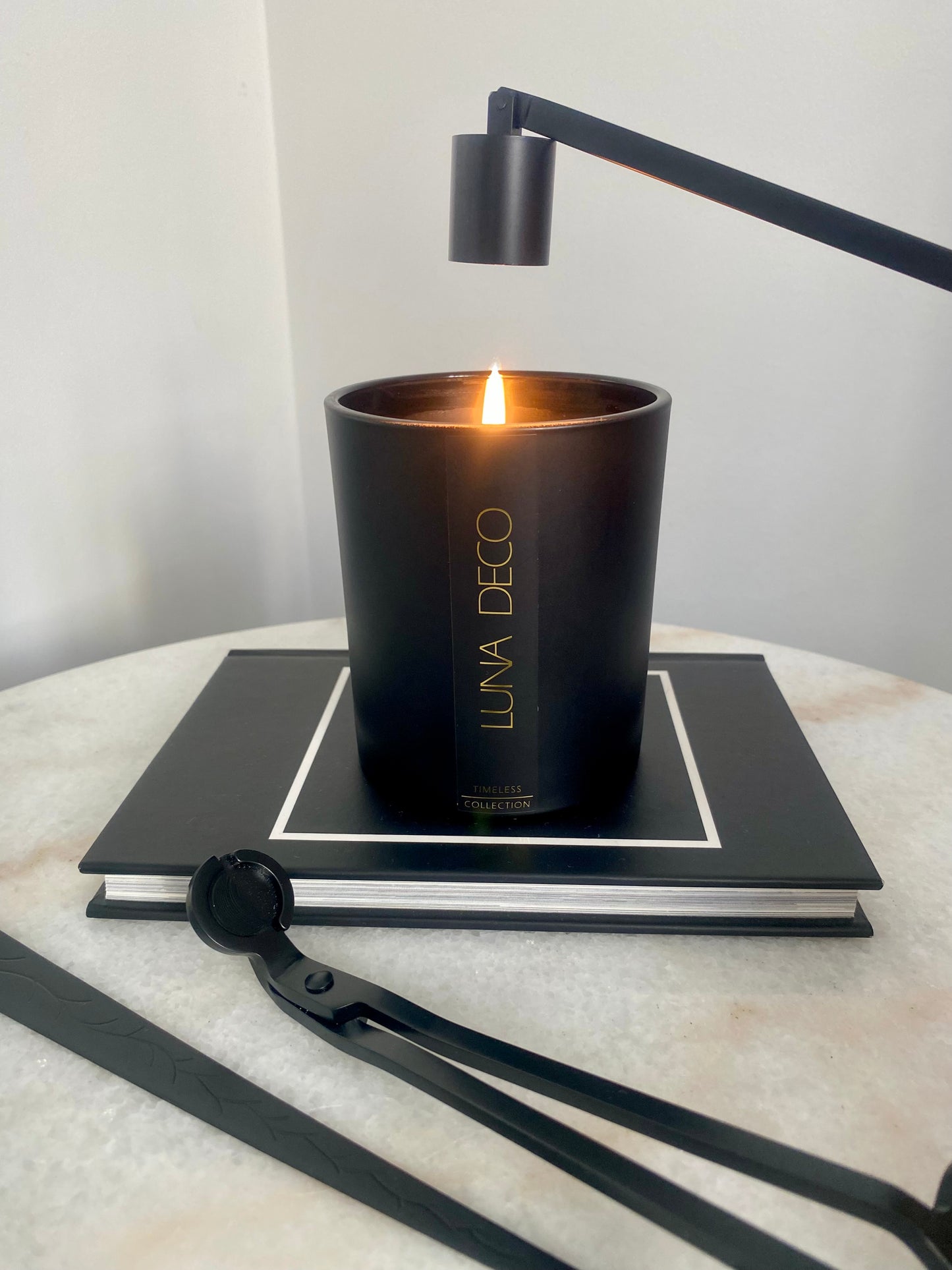Black candle with 'LUNA DECO' branding on a marble surface with a black lamp and candle care set including wick trimmer, candle snuffer and dipper. 
Candle essentials, candle accessories, 
must-have for every true candle lover - designed to enhance the longevity, beauty and ritual pf your candle. 
Luna Deco