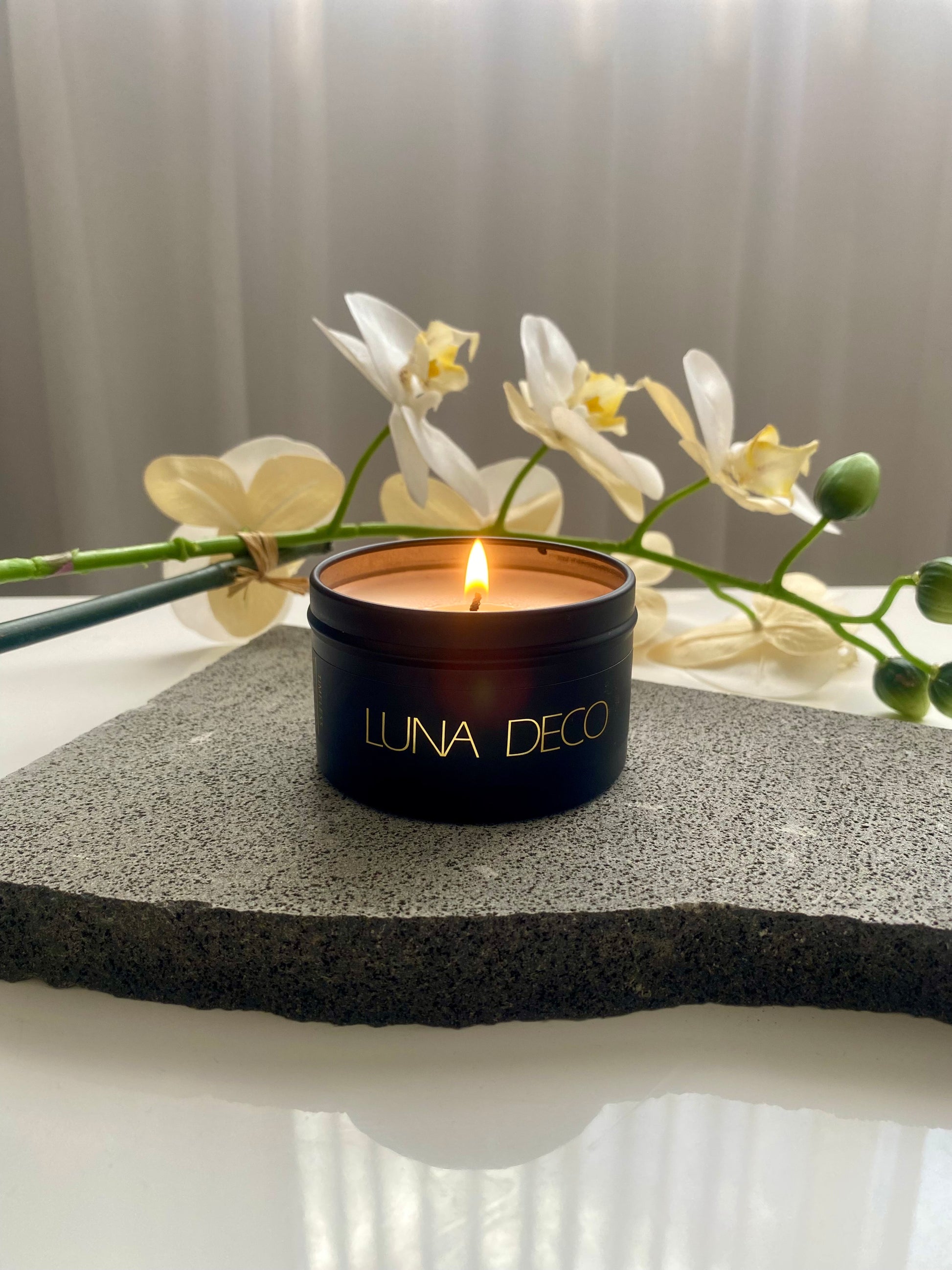 Luna Deco black travel tin candle in a black container with white flowers in the background.
Matte black travel tin candle,  perfect for travel, small spaces or thoughtful gifting.
Minimalist, timeless, elegant design, artisan-made candles. 
Luna Deco. 