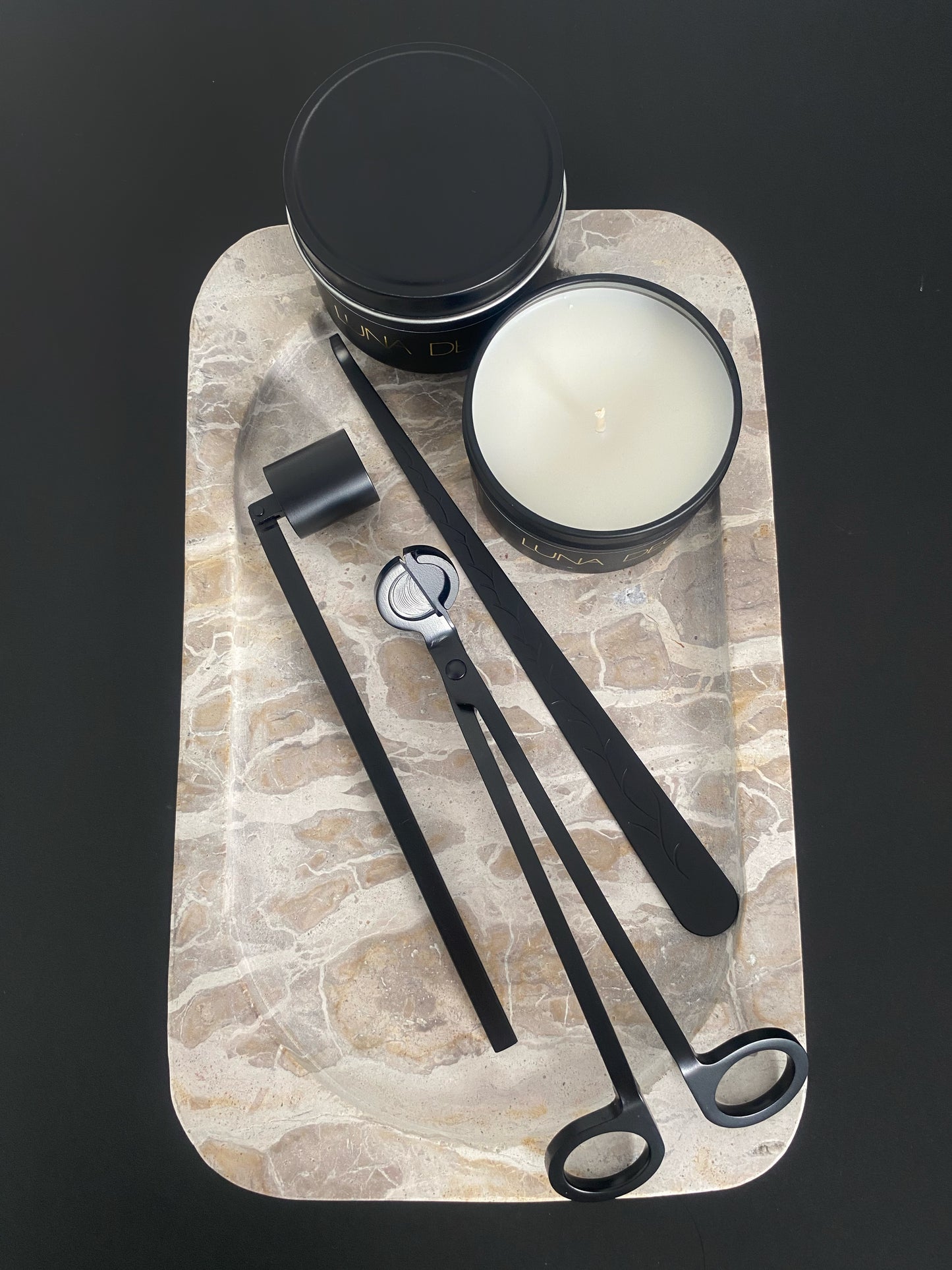 Candle and candle accessories tools on a stone tray with a black background including wick trimmer, candle snuffer and dipper. 
Candle essentials, candle accessories, 
must-have for every true candle lover - designed to enhance the longevity, beauty and ritual pf your candle. 
Luna Deco