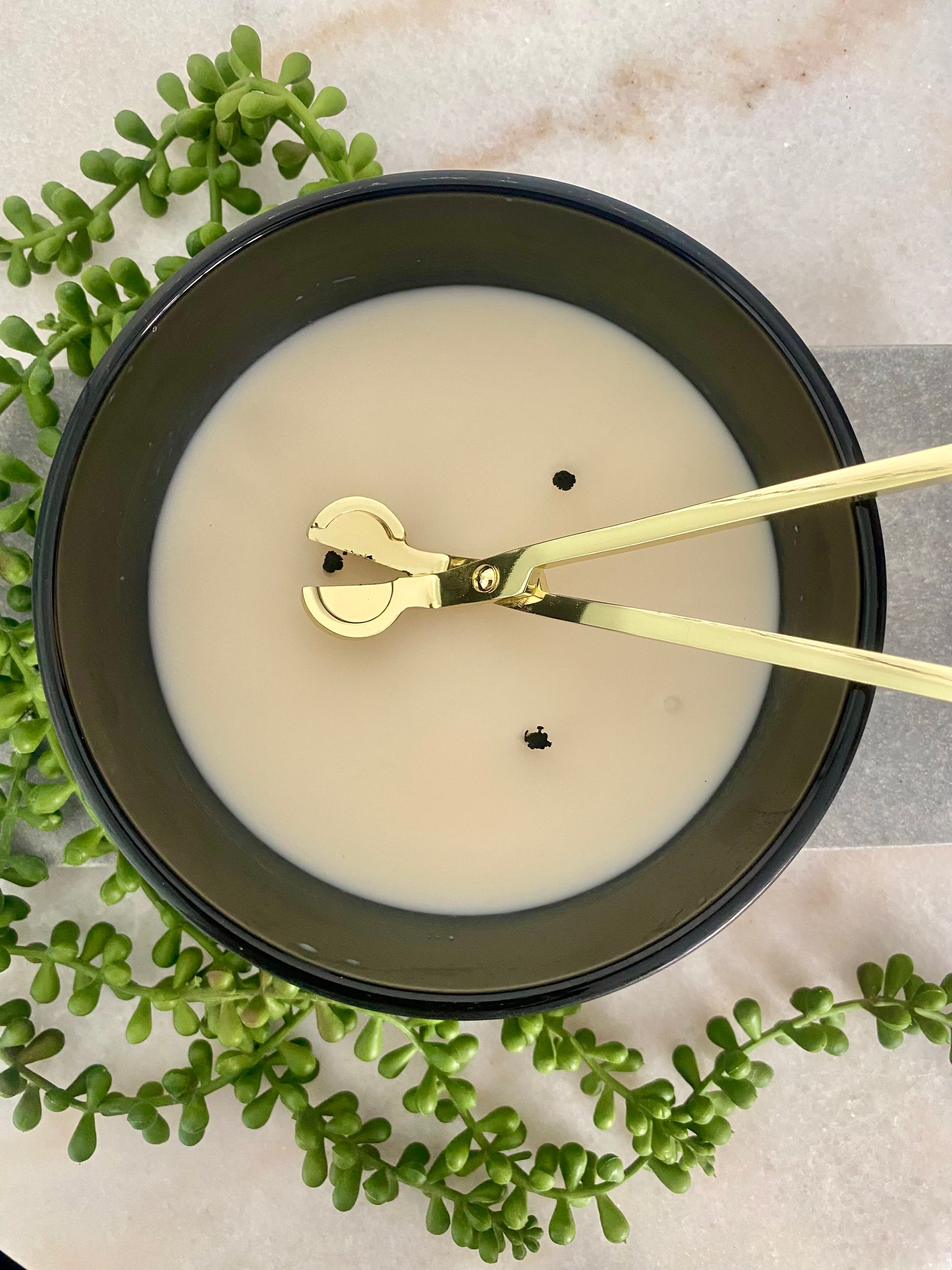 Candle with a 3 wicks and gold wick trimmer on marble surface with green leaves.
Candle essentials, candle accessories, 
must-have for every true candle lover - designed to enhance the longevity, beauty and ritual pf your candle. 
Luna Deco