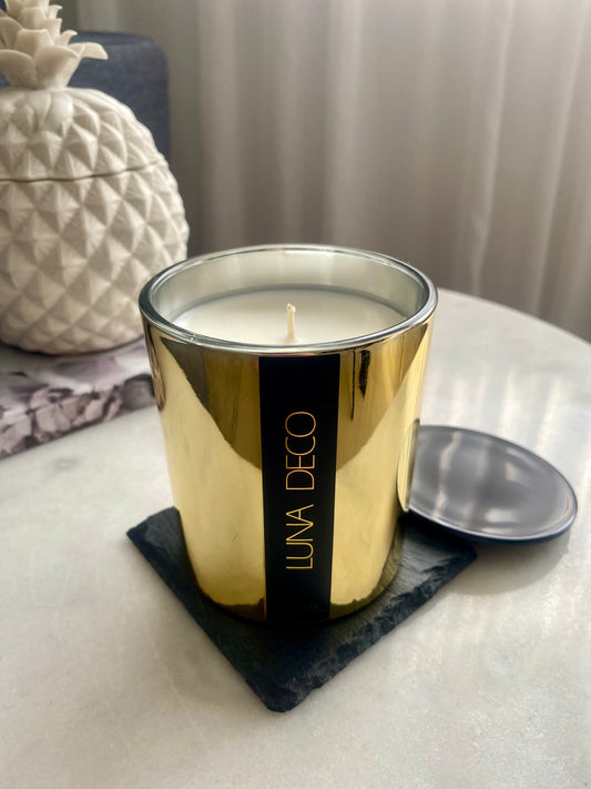 Gold candle with LUNA DECO label on side table with decoration, lifestyle photo. 
Home decor ideas, minimalist style, Australian made soy candle, cozy home, home fragrance, calm and relax, hand-poured soy candles, clean and fresh burn, perfect gift, treat to yourself, stunning decoration piece, 