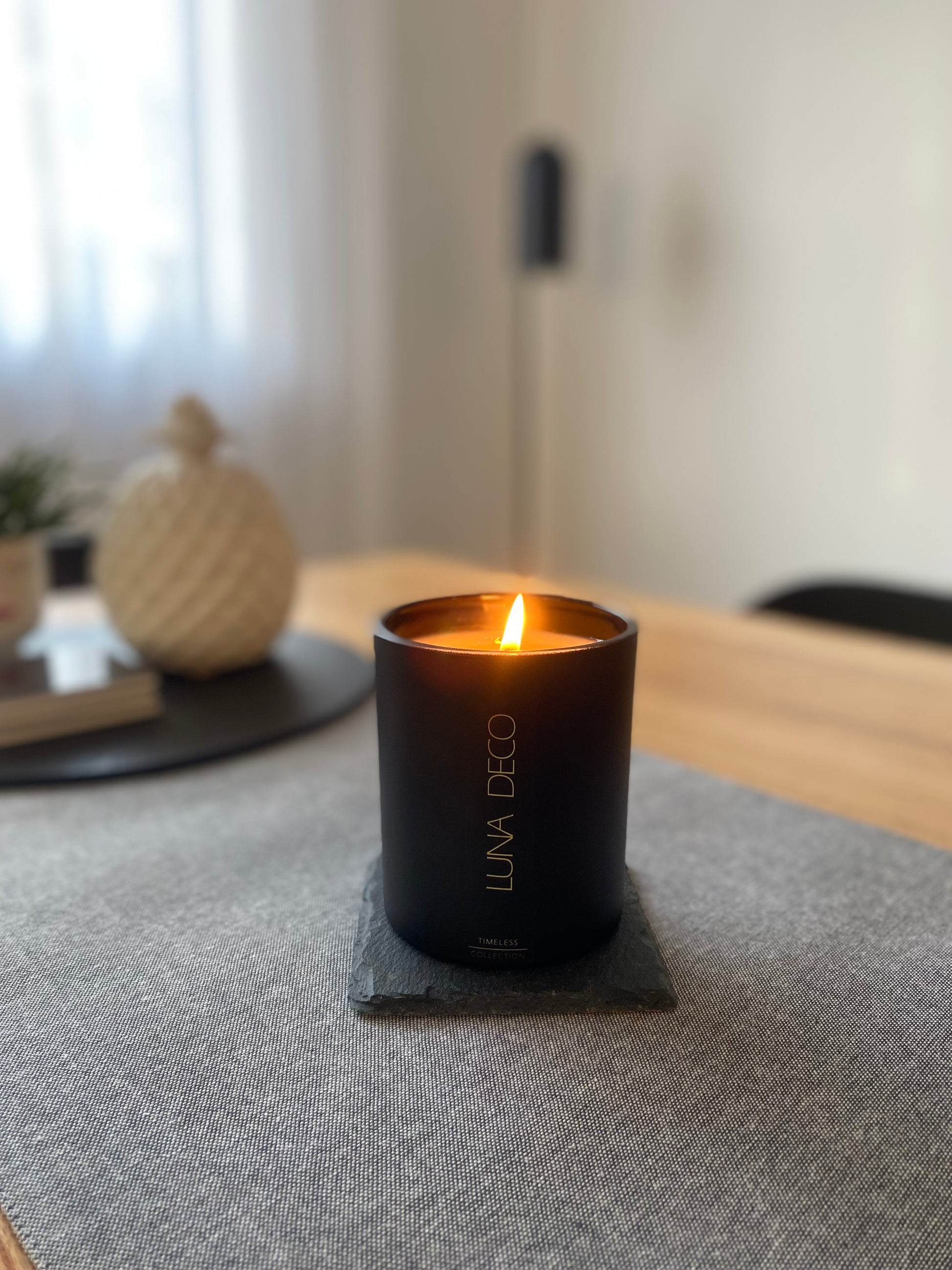 Black matte candle light up,  labelled LUNA DECO, on table - lifestyle shot.
Home decor ideas, minimalist style, Australian made soy candle, cozy home, home fragrance, calm and relax, hand-poured soy candles, clean and fresh burn, perfect gift, treat to yourself, stunning decoration piece, 